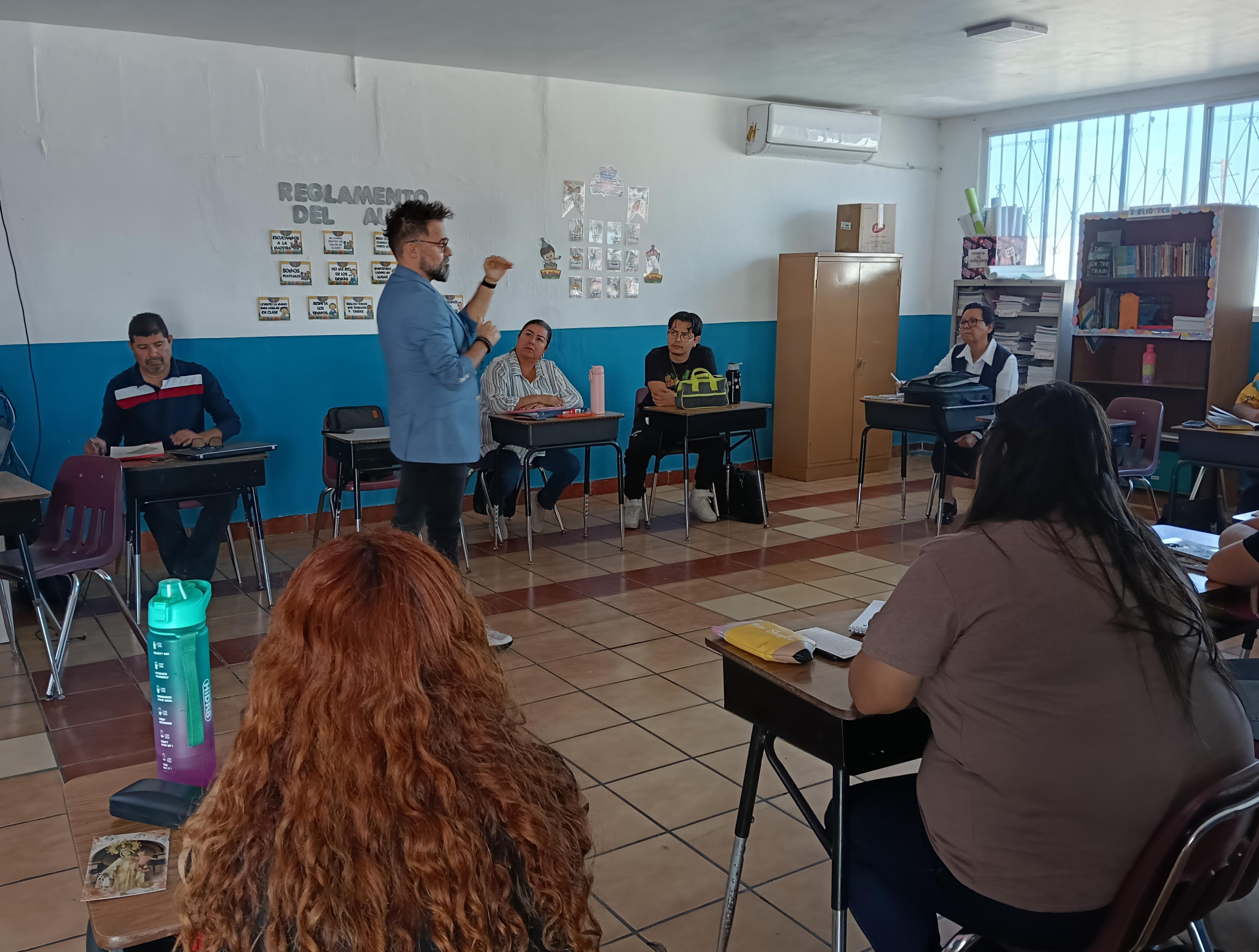 Oscar Villicaña dialoga con participantes adultos sentados en un aula